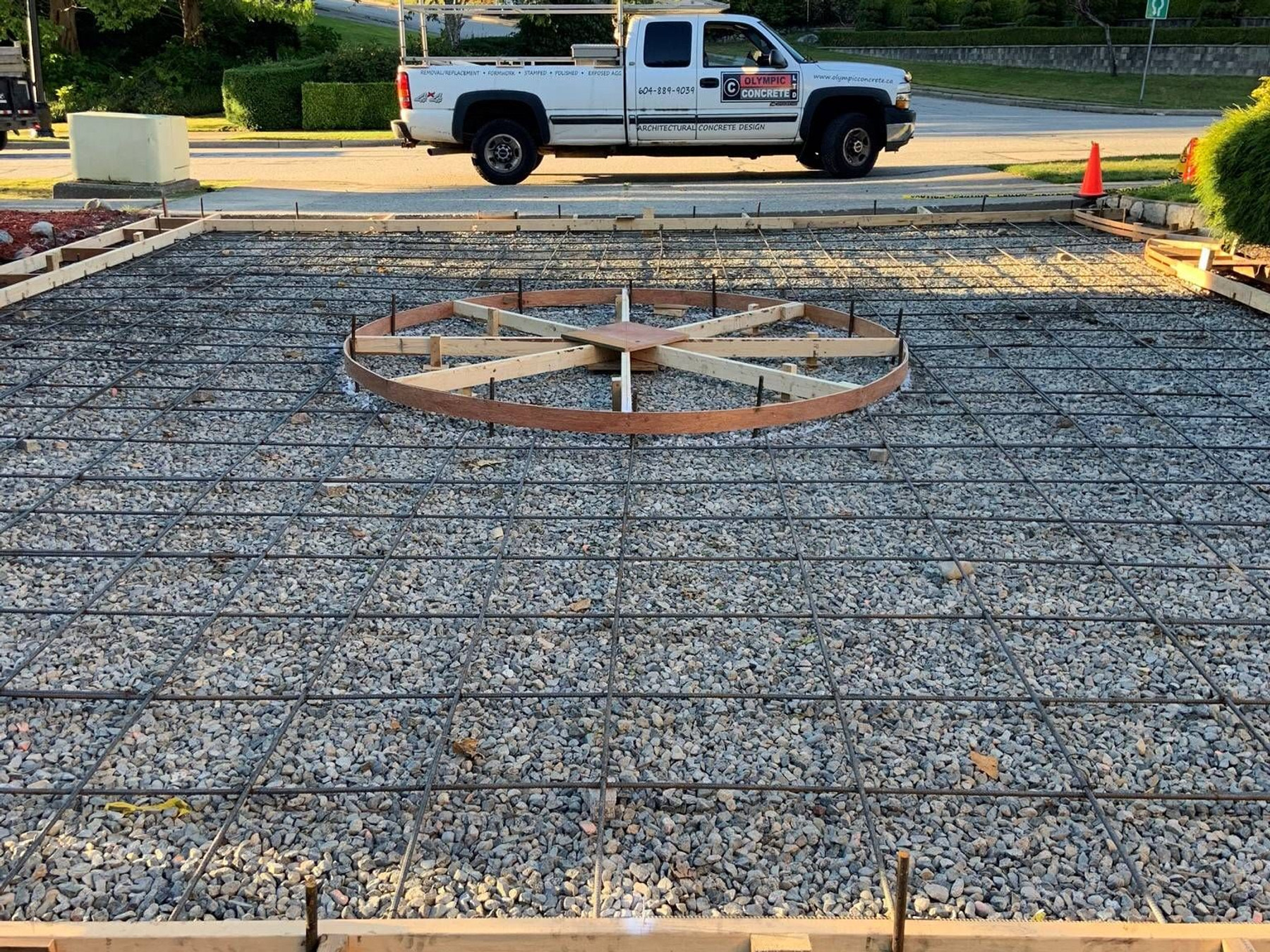 Reinforcing steel grid laid out for a concrete slab, Olympic Concrete truck parked nearby